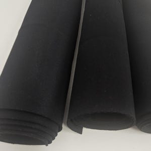 Op de afbeelding: Drie rollen zwarte viltstof. De stof is opgerold en de uiteinden zijn zichtbaar.