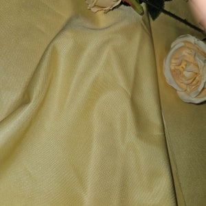 Könnte beinhalten: Nahaufnahme eines hellgelben Stoffes mit einem dezenten Glanz. Der Stoff ist glatt und hat eine leicht knitterige Textur.