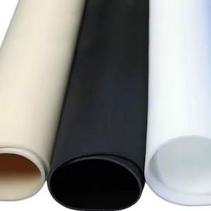 Puede incluir: Tres rollos de tela, uno blanco, uno negro y uno beige. La tela está enrollada y los extremos son visibles.