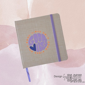 May include: A gray journal with a purple elastic band and a matching ribbon bookmark. The cover features a circular design with the words "GOOD VIBES ONLY" in purple and orange, with a blue heart. Design by BLACK Kreative.