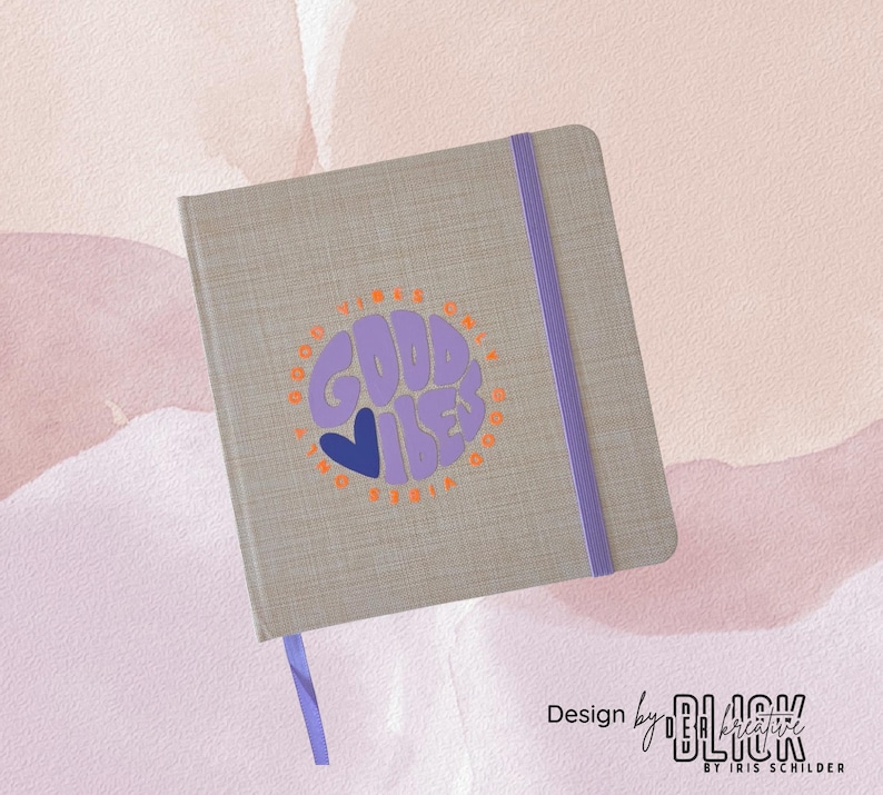 May include: A gray journal with a purple elastic band and a matching ribbon bookmark. The cover features a circular design with the words "GOOD VIBES ONLY" in purple and orange, with a blue heart. Design by BLACK Kreative.