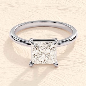 May include: A silver ring with a square-shaped diamond set in a prong setting.