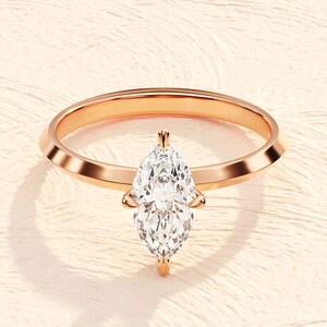 May include: A rose gold engagement ring with a pear-shaped diamond.