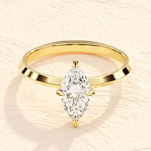 May include: A gold engagement ring with a large, clear marquise-shaped diamond.