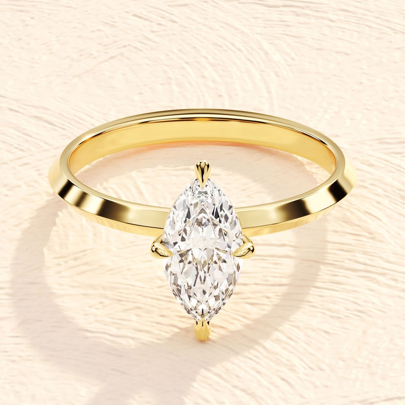 May include: A gold engagement ring with a large, clear marquise-shaped diamond.