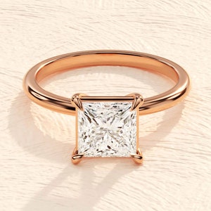 May include: A rose gold engagement ring with a square-shaped diamond.