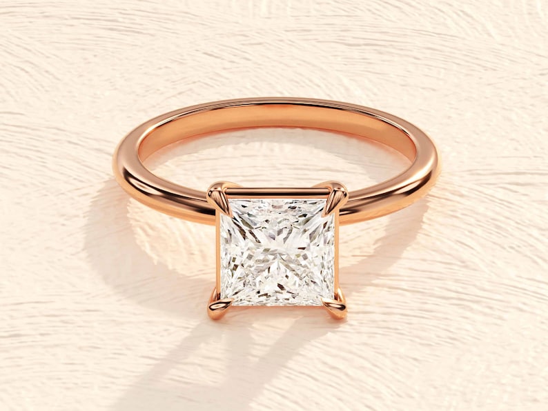 May include: A rose gold engagement ring with a square-shaped diamond.