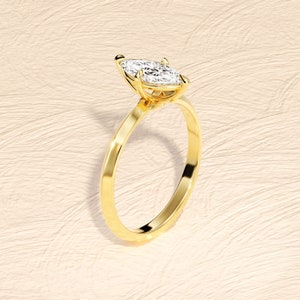 May include: A gold engagement ring with a marquise-shaped diamond.