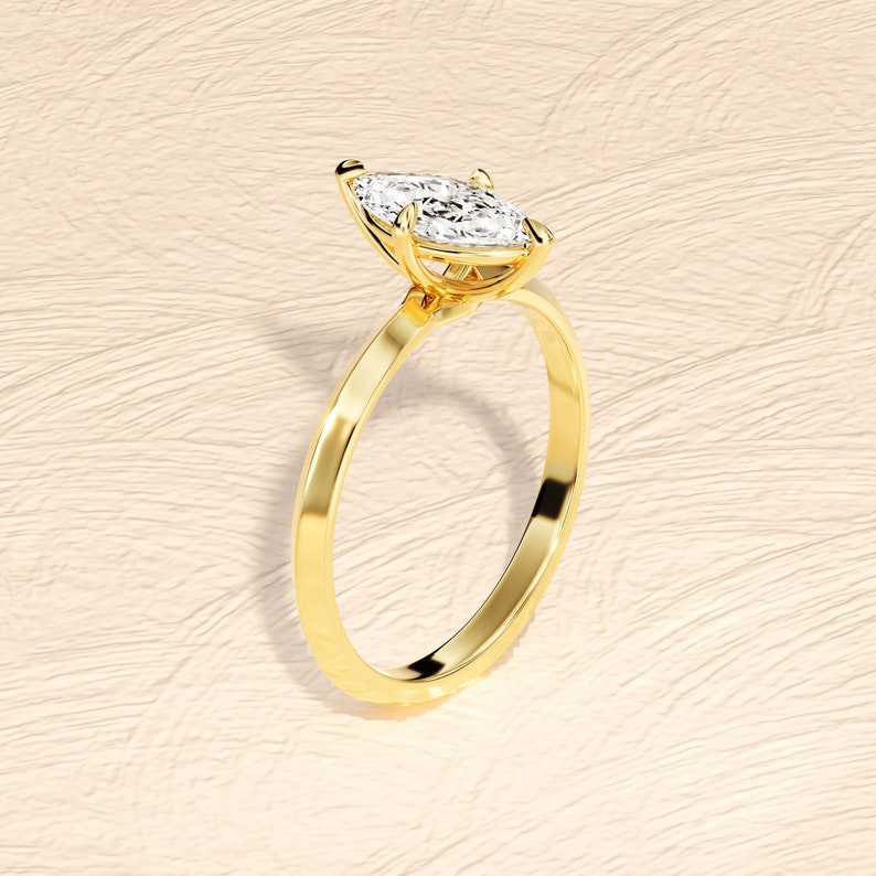 May include: A gold engagement ring with a marquise-shaped diamond.