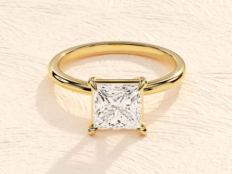 May include: A gold ring with a square-shaped diamond set in a prong setting.