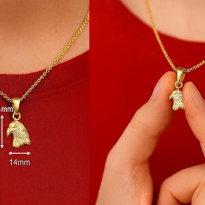 May include: A gold-colored pendant necklace featuring an eagle head design. The pendant measures 12mm x 14mm and hangs from a delicate chain. The necklace is displayed against a red background.