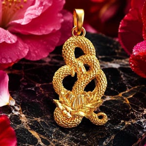 Könnte beinhalten: Ein goldener Anhänger in Form einer gewundenen Schlange mit einer texturierten, schuppenartigen Oberfläche. Die Schlange ist um eine blühende Lotusblume an der Basis gewickelt. Der Anhänger besitzt eine polierte Goldöse zur Befestigung.