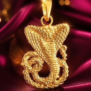 Op de afbeelding: Een goudkleurige hanger in de vorm van een opgerolde cobra met een textuur die lijkt op schubben. De hanger heeft een uitgespreide kap en een gedetailleerde kop, met een gladde, gepolijste hangerring aan de bovenkant voor een ketting.