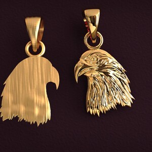 May include: Two gold-colored eagle head pendants. One pendant is a solid silhouette, while the other features detailed feathering. Both have a loop for a chain. The pendants are displayed against a dark background.