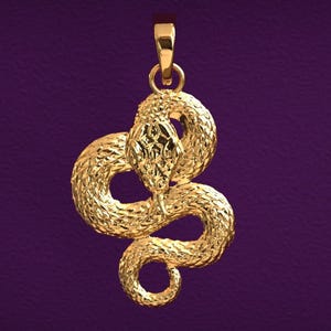 Könnte beinhalten: Ein goldfarbener Anhänger in Form einer aufgerollten Schlange. Der Schlangenkopf ist mit strukturierten Schuppen versehen, und der Körper ist spiralförmig gewunden. Der Anhänger hat oben eine Schlaufe für eine Kette.