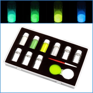 May include: A set of eight small glass bottles with different colored glow-in-the-dark powders. The bottles are arranged in a black plastic case with a red and white paintbrush and a green circle.