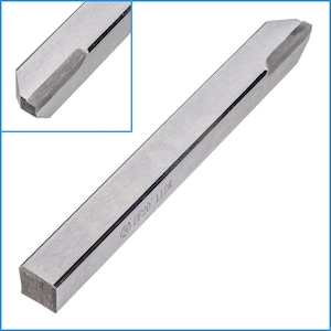 Può includere: Uno strumento in metallo argentato con una punta appuntita e una base quadrata. Lo strumento ha una linea nera che corre lungo il centro e il testo "(B) UF20 - 112R" è inciso sul lato.