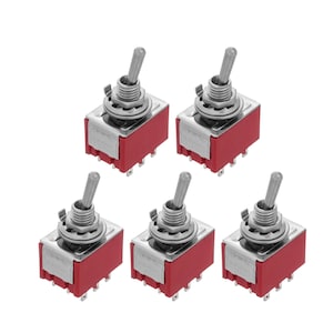Op de afbeelding: Vijf zilveren schakelaars met rode kunststof behuizingen. De schakelaars staan ​​in de uit-stand.