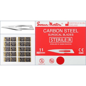 Peut inclure: Une boîte rouge et blanche de lames chirurgicales en acier au carbone stériles, étiquetée "Swann-Morton" et "STERILE R". La boîte contient 11 lames, avec un numéro de référence 0203. Les lames sont emballées individuellement dans de petites enveloppes bleues et dorées.