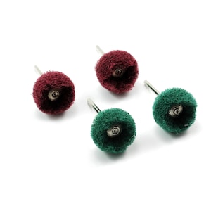 May include: Four small buffing wheels in burgundy and green. Each wheel has a metal stem and a central hole. The wheels are arranged on a white background, highlighting their texture and colour variations.