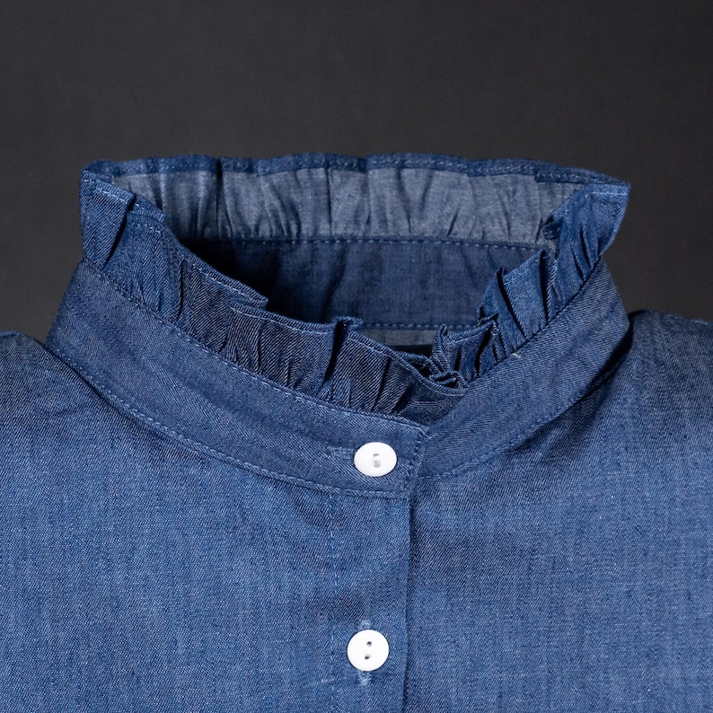 K&ouml;nnte beinhalten: Ein blaues Jeanshemd mit R&uuml;schenkragen und wei&szlig;en Kn&ouml;pfen.