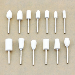 May include: A set of 15 white sanding drum attachments for a rotary tool. The drums are various shapes and sizes, including round, cone, and cylinder.