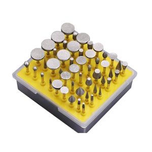 May include: A yellow plastic case filled with a variety of small, silver-colored diamond-tipped rotary tools. The tools are arranged in rows and columns, and the case has a clear lid.