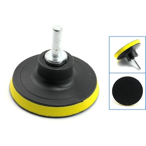 May include: A black and yellow sanding pad with a metal shaft. The pad is designed for use with a drill or other rotary tool. It is used for sanding and polishing surfaces.