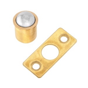 May include: A brass magnetic door catch with a round, silver-colored magnetic ball. The catch is designed to hold a door closed.