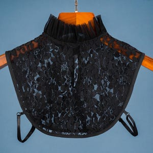 May include: Black lace collar with a ruffled trim and adjustable straps. The collar is made of delicate lace and has a soft, feminine look.