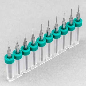 May include: A set of ten drill bits in clear plastic cases with turquoise caps. The drill bits are arranged in a row, with the smallest bit on the left and the largest bit on the right.