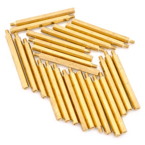 May include: A group of 20 gold-coloured metal standoffs, arranged in a fan shape. The standoffs are approximately 2.5 cm long and have a hexagonal head.