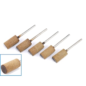 Könnte beinhalten: Sechs braune Schleifhülsen mit Metallstiften. Die Hülsen sind zylindrisch und haben eine raue Textur. Die Stifte sind silberfarben und an einem Ende an die Hülsen befestigt.