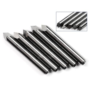 May include: A set of six silver-coloured, pointed, metal tools with a rounded tip. The tools are arranged in a fan shape, with the tips pointing towards the right side of the image.