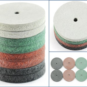 Puede incluir: Un conjunto de 10 discos de lija de varios colores, incluyendo gris, verde, marrón y negro. Los discos están apilados en una pila, con los discos grises en la parte superior. Los discos son todos del mismo tamaño y tienen un pequeño agujero en el centro.