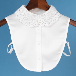 Puede incluir: Collar de encaje blanco con cierre de botón. El collar está hecho de una tela suave y ligera y tiene un delicado borde de encaje.