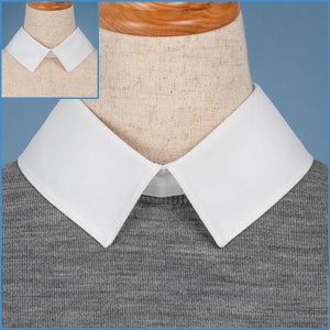May include: A white detachable collar with a pointed shape, worn on a gray sweater. The collar is made of a smooth fabric and has a clean, crisp look.