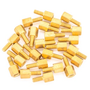 May include: A group of 20 gold-coloured metal standoffs with a hexagonal base and a threaded screw. The standoffs are arranged in a random pattern on a white background.