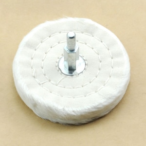 May include: A white cotton buffing wheel with a metal center shaft. The wheel is stitched around the edge and has a fluffy texture.