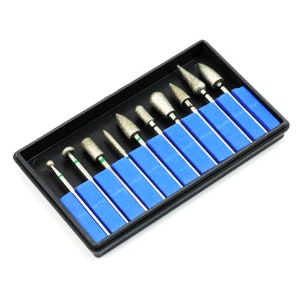 May include: A set of ten diamond-tipped drill bits in a black plastic case with blue foam inserts. The drill bits are silver with green bands.