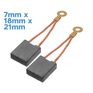 Könnte beinhalten: Zwei Kohlebürsten mit Kupferdrahtleitungen und vergoldeten Steckverbindern. Die Bürsten sind rechteckig und grau. Die Abmessungen betragen 7 mm x 18 mm x 21 mm.