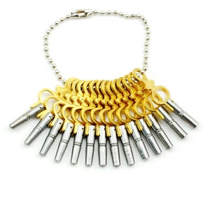 May include: A set of gold-colored ring sizers and silver-colored sizing tools attached to a silver ball chain. The ring sizers are arranged in a fan shape, with each one having a different size.