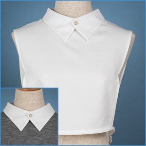 Può includere: Un colletto bianco staccabile con uno stile a punta con bottoni. Il colletto ha un bottone di perla al centro.