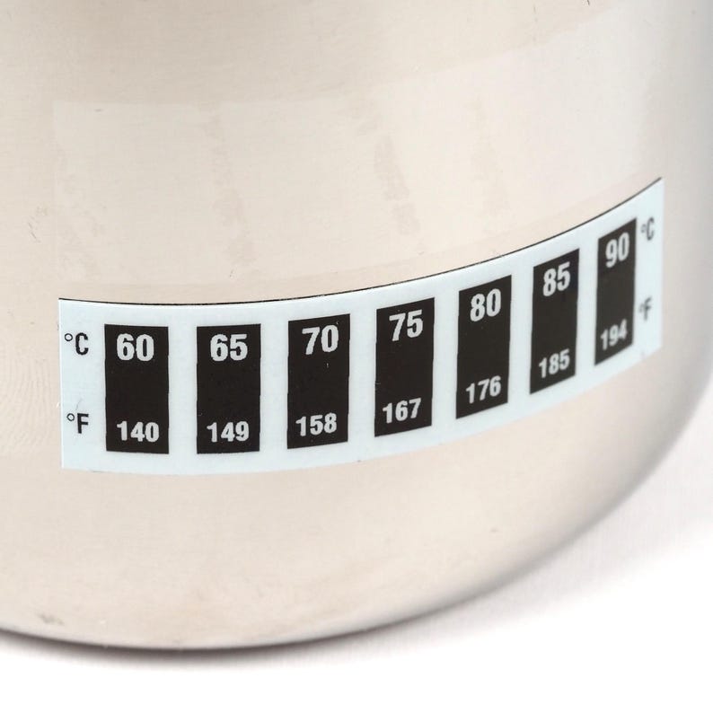 May include: A stainless steel pot with a temperature gauge on the side. The gauge shows temperatures in both Celsius and Fahrenheit. The gauge reads from 60&deg;C to 90&deg;C and 140&deg;F to 194&deg;F.