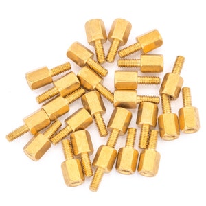 May include: A group of 20 gold-coloured metal standoffs with hexagonal heads and threaded shafts. The standoffs are arranged in a random pattern on a white background.
