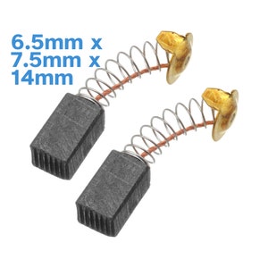 Könnte beinhalten: Zwei schwarze Kohlebürsten mit federbelasteten Drahtleitungen. Die Bürsten sind rechteckig und haben eine geriffelte Oberfläche. Die Abmessungen betragen 6,5 mm x 7,5 mm x 14 mm.