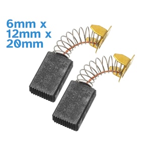 Könnte beinhalten: Zwei schwarze Kohlebürsten mit goldfarbenen Federanschlüssen. Die Bürsten sind rechteckig und haben eine strukturierte Oberfläche. Die Abmessungen der Bürsten betragen 6 mm x 12 mm x 20 mm.