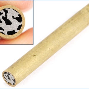 May include: A brass pen blank with a decorative, intricate design cut into the end. The design is a silver-colored, stylized pattern.