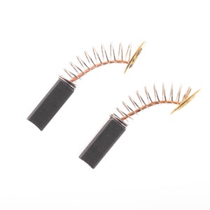 May include: Two black carbon brushes with copper spring coils and gold-colored metal contacts. The brushes are used in power tools and other electrical equipment.