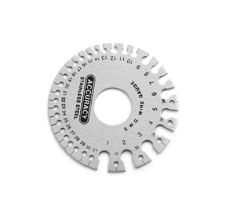 Puede incluir: Una herramienta de calibre de alambre circular de plata. La herramienta est&aacute; marcada con n&uacute;meros del 1 al 38, y el texto "S.W.G. WIRE GAUGE" est&aacute; impreso en la herramienta. La herramienta est&aacute; hecha de acero inoxidable y est&aacute; etiquetada como "ACCURACY".